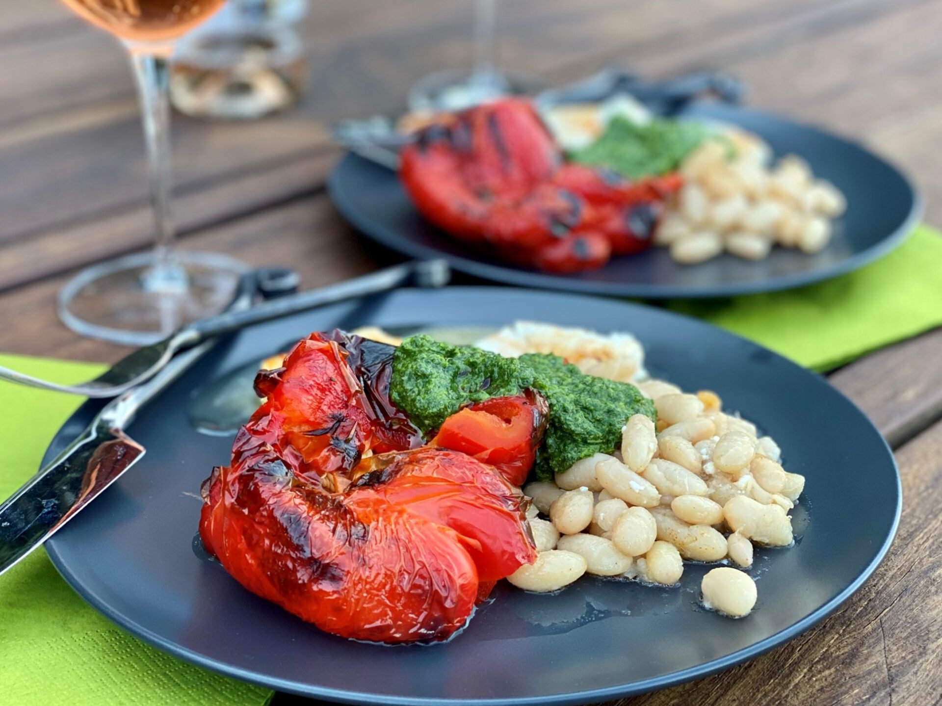 Plates of roasted red peppers, white beans, feta, and green herb sauce.