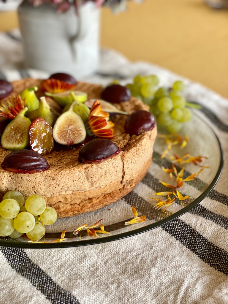 Flourless walnut spice cake adorned with fall fruits and flowers.