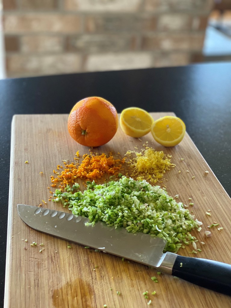 chopped green garlic, orange and lemon zest on cutting board