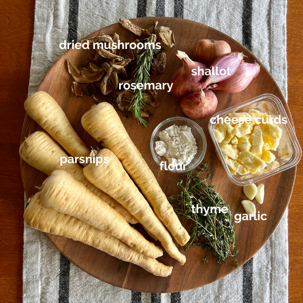 Image of all the ingredients needed to make the parsnip poutine + rich mushroom gravy: parsnips, dried mushrooms, rosemary, shallot, flour, thyme, garlic, and cheese curds. 