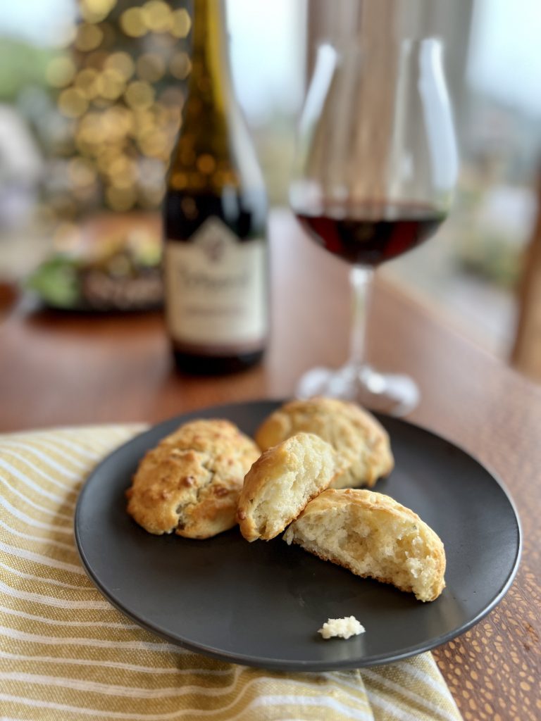 olive oil drop biscuits on a plate next to a bottle of wine.