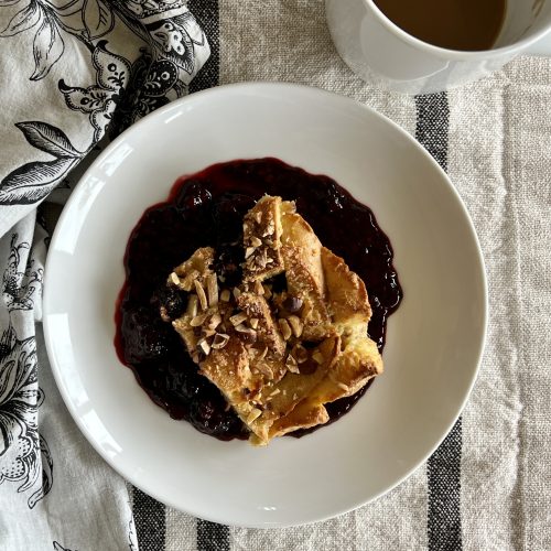 a plate of baked berry French toast and a cup of coffee