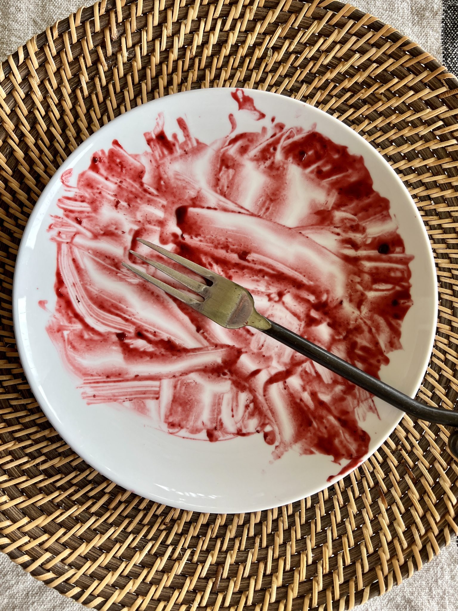 An empty plate with berry compote streaks.