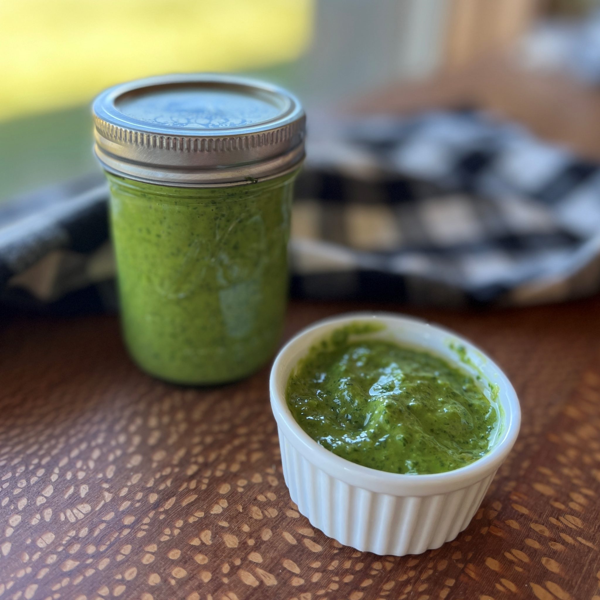 A jar and a bowl of summery green basil sauce.