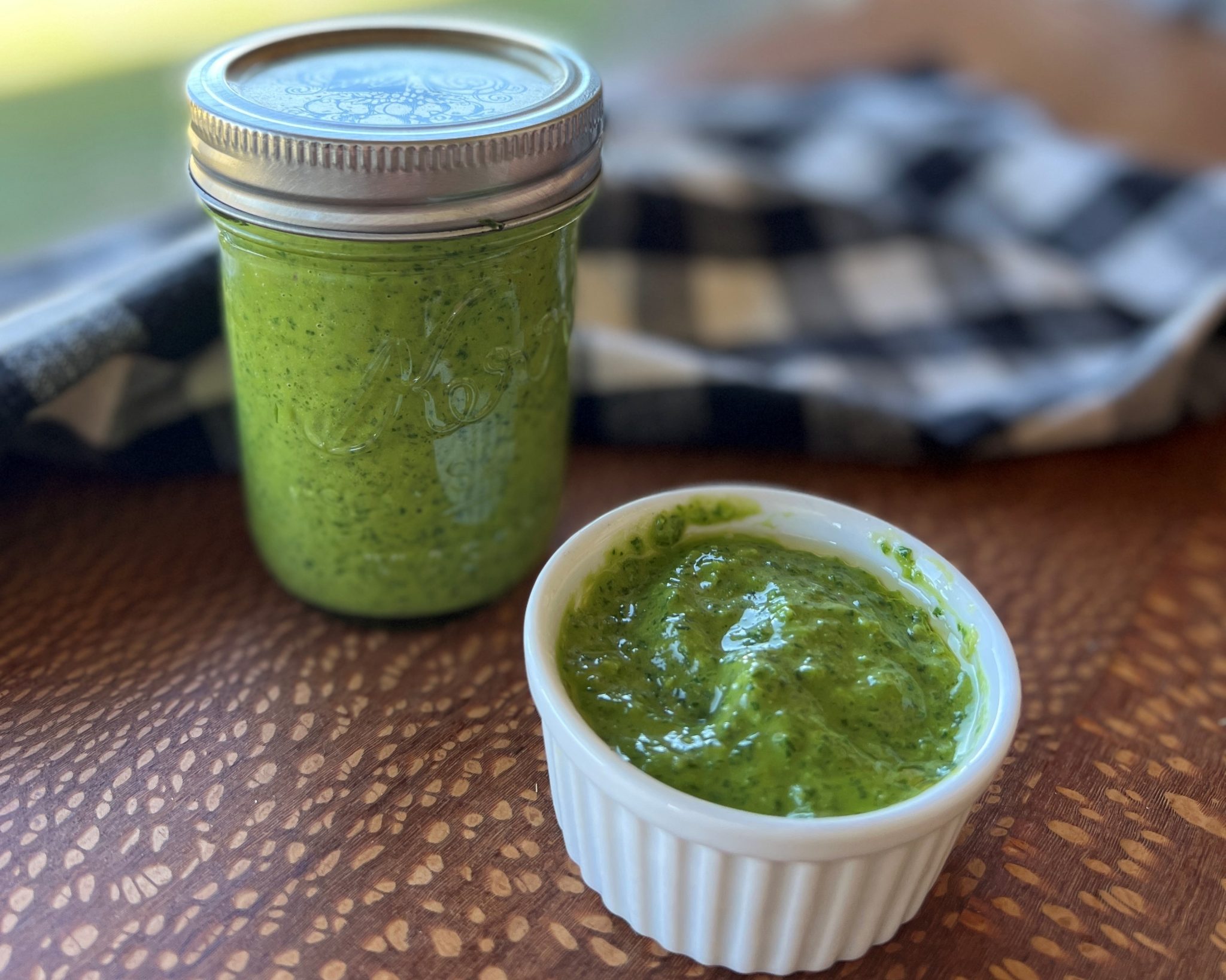 A jar and bowlful of summery green basil sauce.