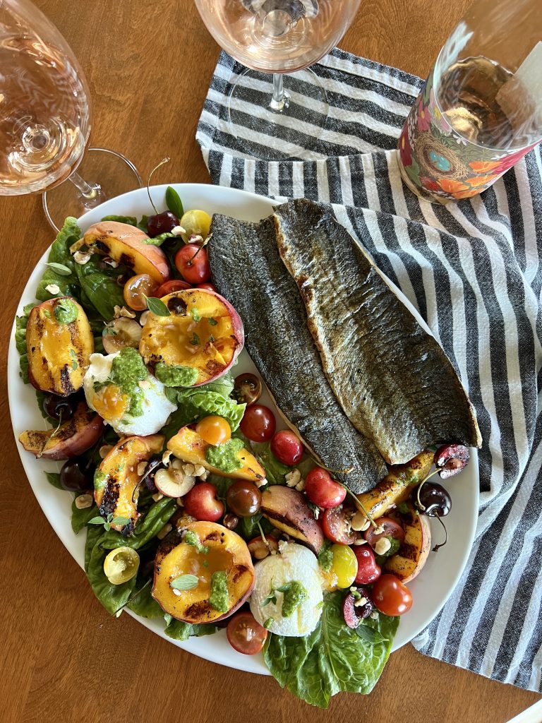 A platter of grilled peach + ricotta salad and grilled trout.