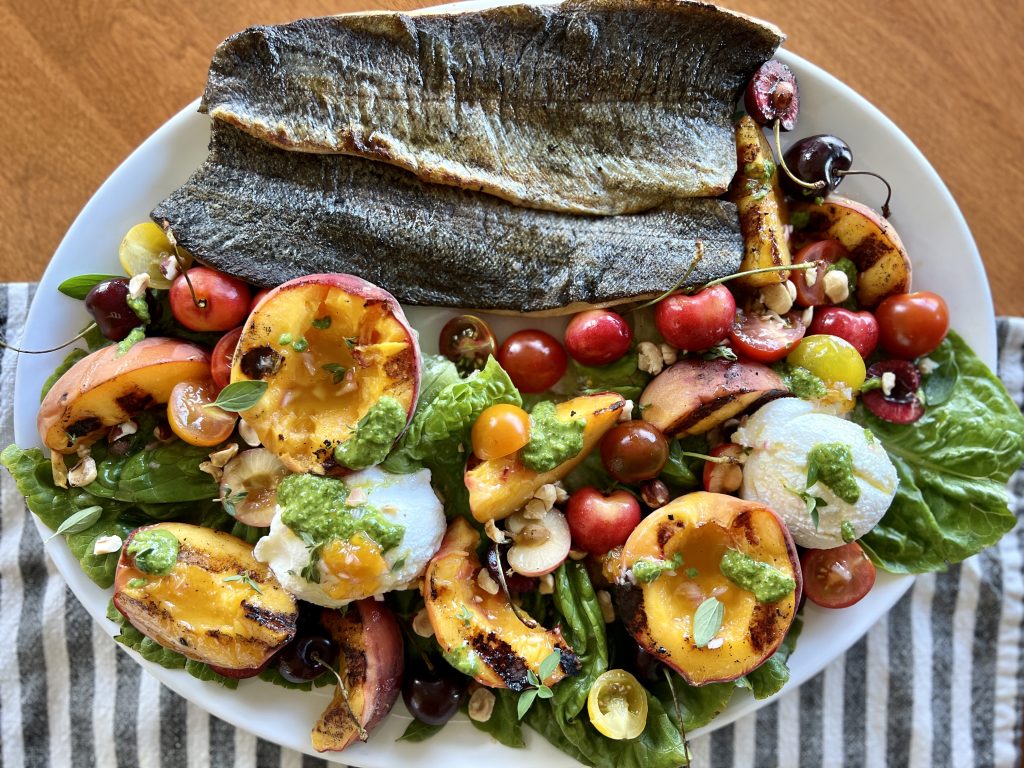 A platter of grilled peach + ricotta Salad and grilled trout.