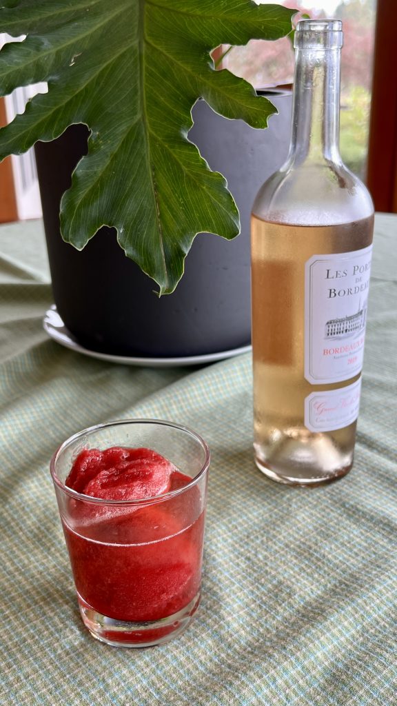 Raspberry sorbet and Rosé cocktail next to a bottle of Rosé and a houseplant.