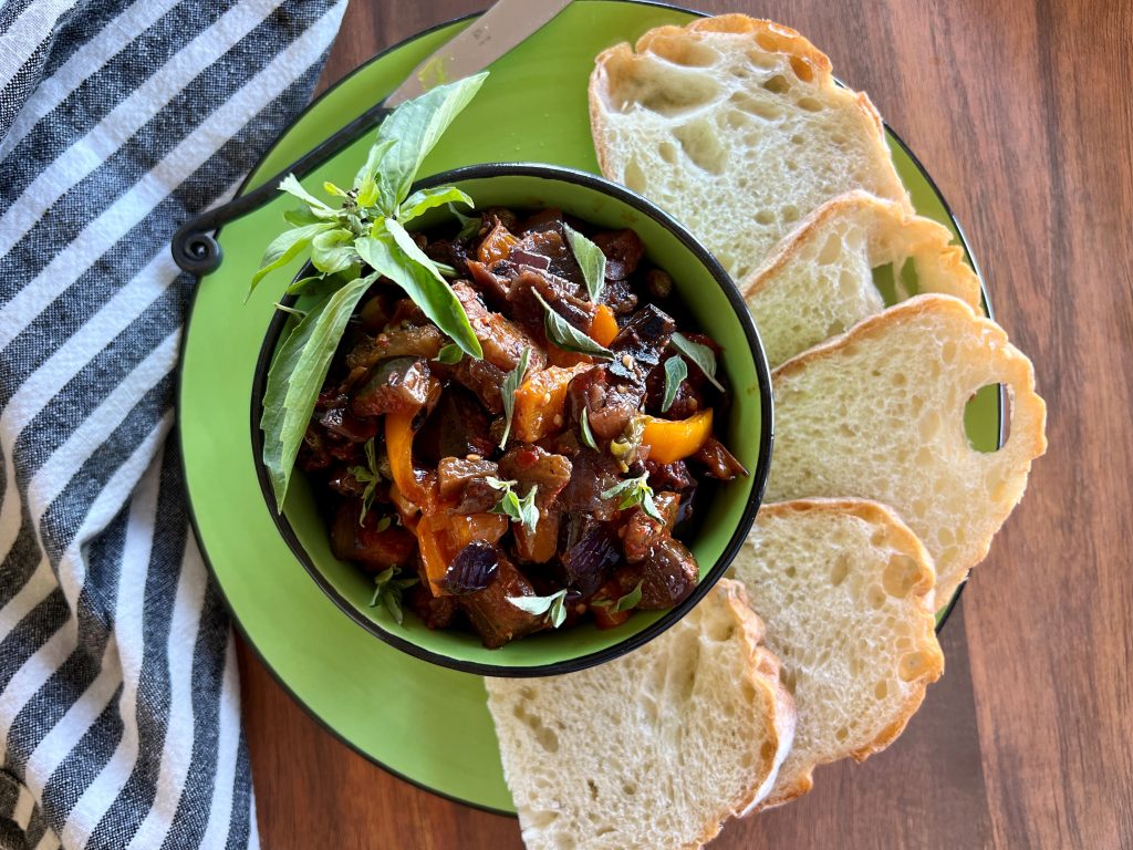 A bowl of caponata with slices of bread
